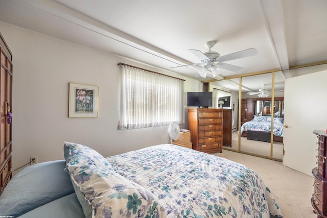 bedroom featuring beamed ceiling, a closet, light colored carpet, and ceiling fan