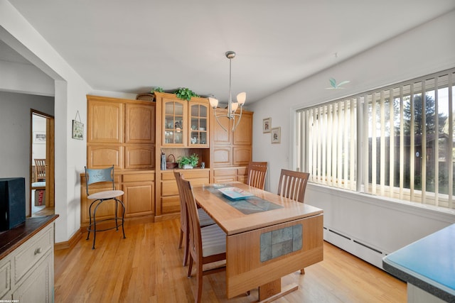 dining area featuring a baseboard radiator, light hardwood / wood-style flooring, and an inviting chandelier