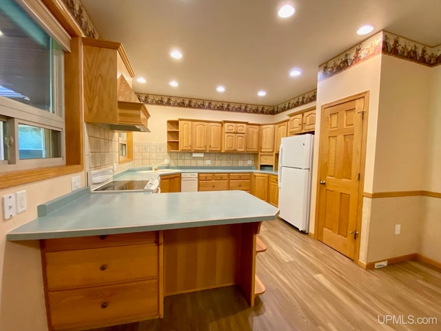 kitchen featuring kitchen peninsula, backsplash, light brown cabinetry, light wood-type flooring, and white appliances