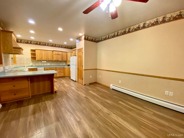 kitchen with kitchen peninsula, ceiling fan, light wood-type flooring, white fridge, and baseboard heating