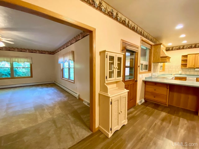 kitchen with baseboard heating, hardwood / wood-style floors, decorative backsplash, and ceiling fan