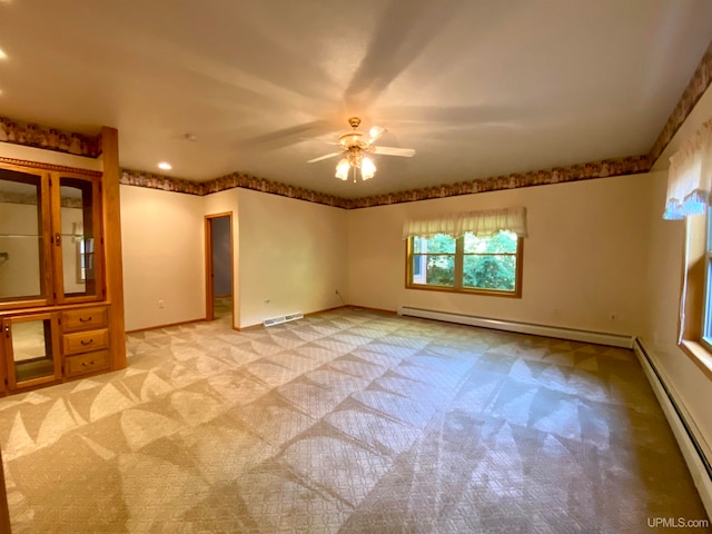 carpeted empty room with a baseboard heating unit and ceiling fan