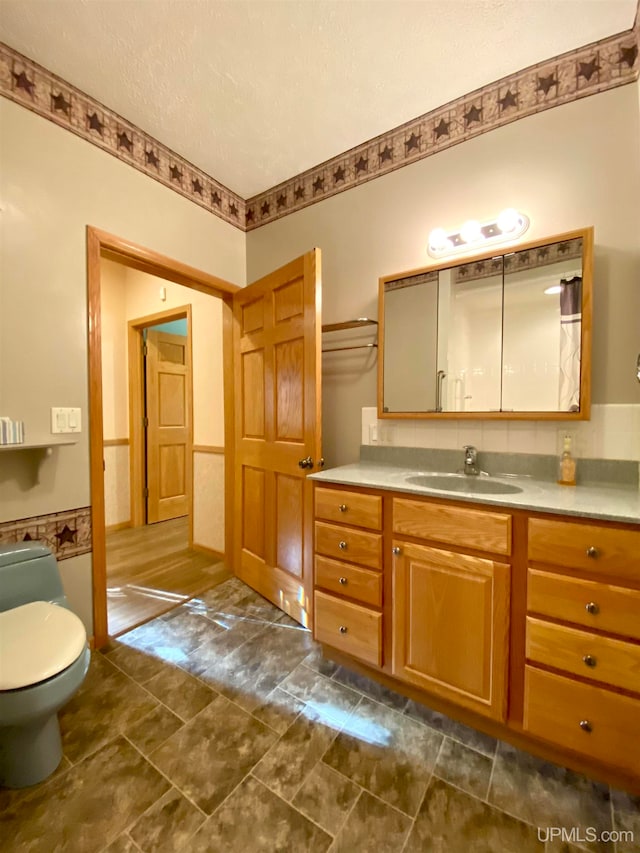 bathroom featuring vanity, toilet, and a textured ceiling