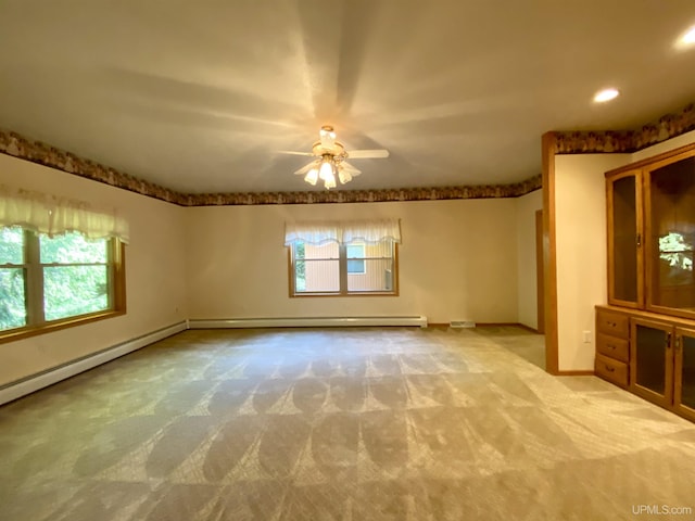 unfurnished room featuring ceiling fan, a wealth of natural light, and light carpet