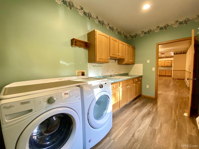 washroom with washer and clothes dryer, a sink, light wood-style floors, cabinet space, and baseboards