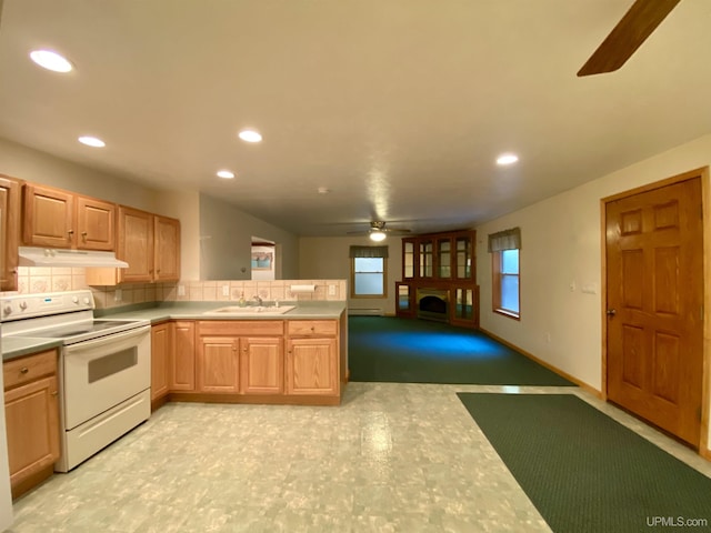 kitchen with a ceiling fan, a sink, a fireplace, electric range, and under cabinet range hood