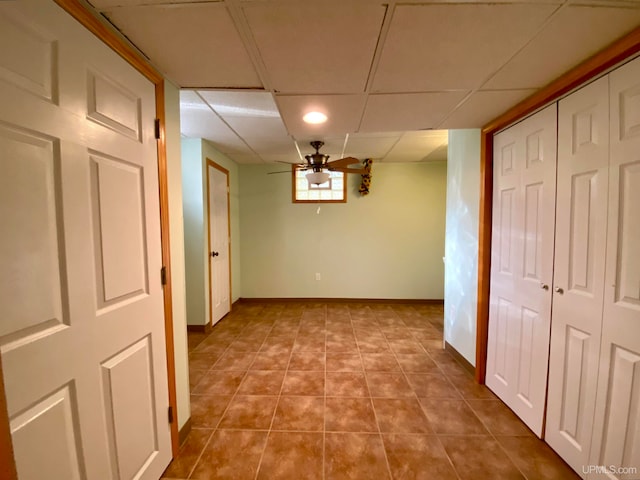 hall with a paneled ceiling and tile patterned flooring