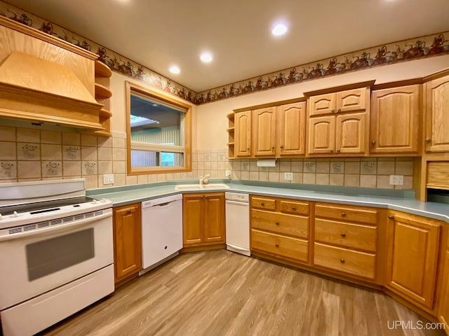 kitchen with white appliances, sink, light hardwood / wood-style floors, decorative backsplash, and premium range hood