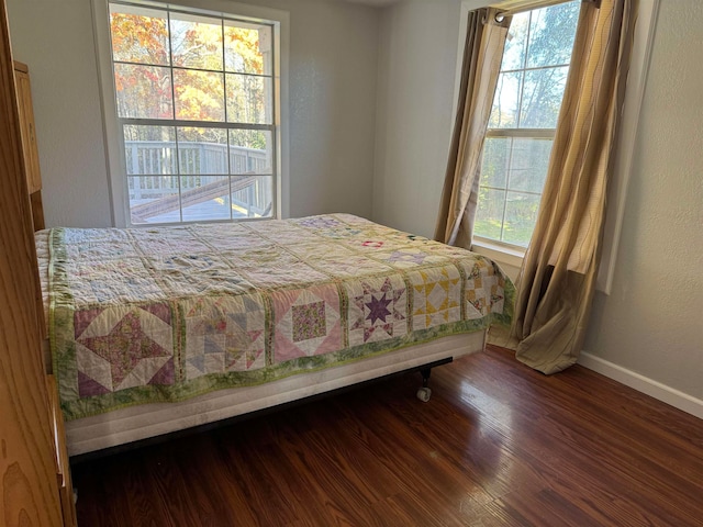 bedroom with multiple windows and dark hardwood / wood-style flooring