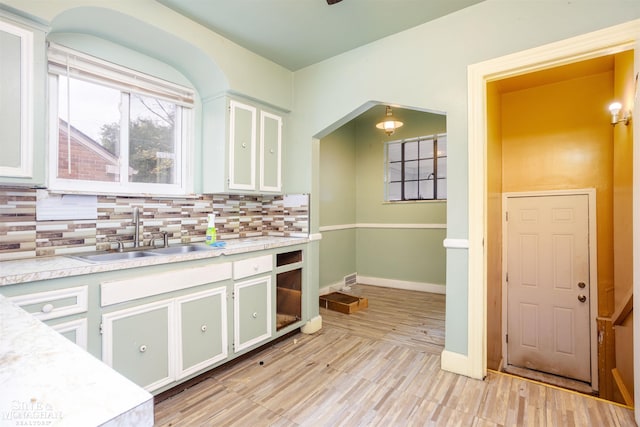 kitchen with light hardwood / wood-style flooring, tasteful backsplash, sink, and white cabinets