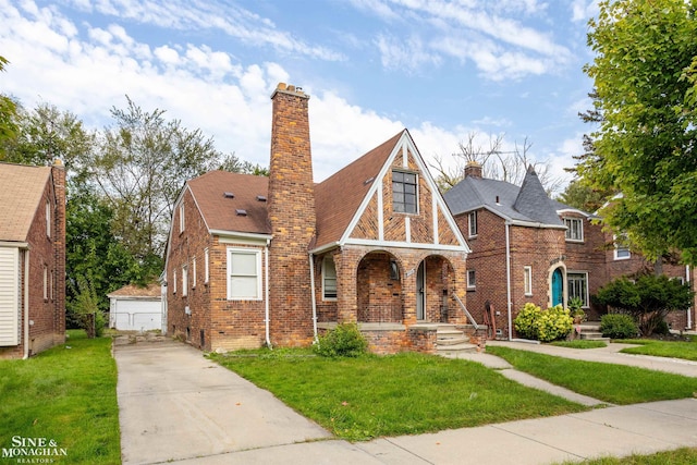 english style home with a garage, a front lawn, and an outdoor structure