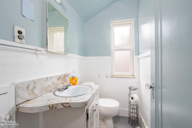 bathroom featuring vanity, toilet, a healthy amount of sunlight, and vaulted ceiling