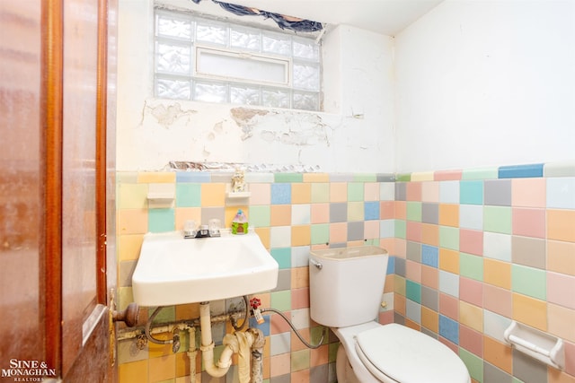 bathroom with tile walls, sink, and toilet