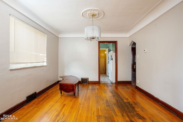 unfurnished room featuring a notable chandelier and hardwood / wood-style flooring