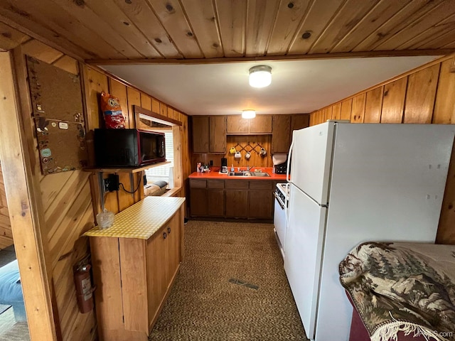 kitchen with wood walls, white refrigerator, and dark colored carpet