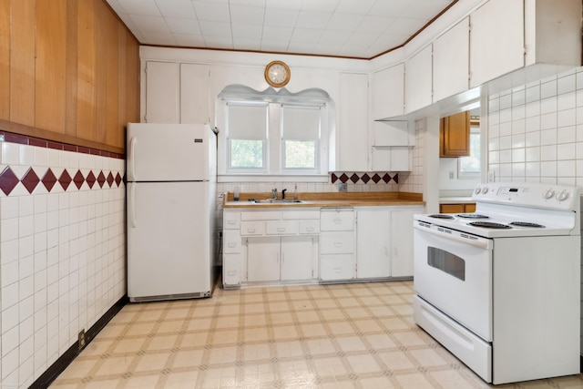 kitchen with white cabinets, sink, tile walls, and white appliances