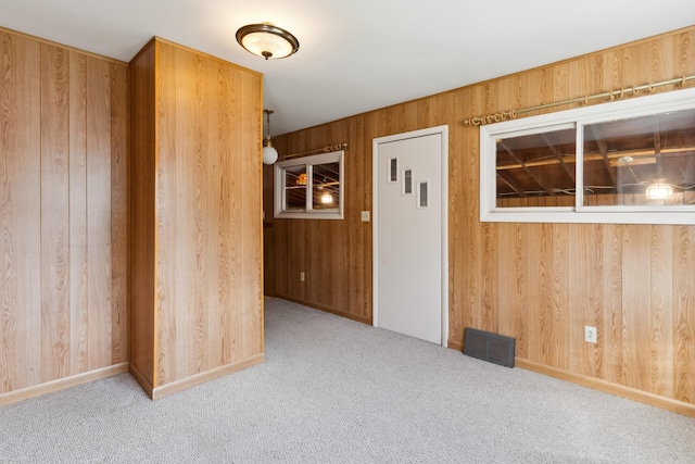 carpeted spare room featuring wood walls