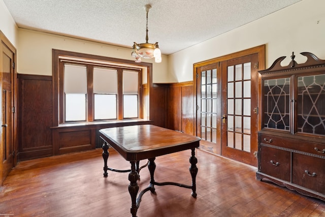 interior space featuring french doors, a textured ceiling, hardwood / wood-style flooring, and a notable chandelier