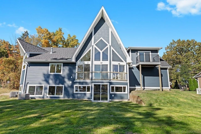 back of property with a balcony, cooling unit, and a lawn