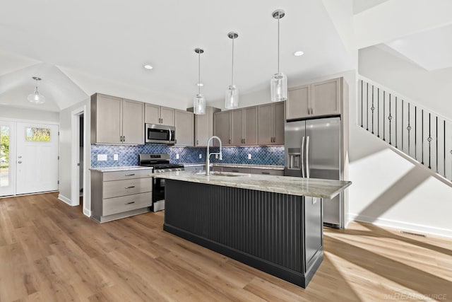 kitchen with a kitchen island with sink, light hardwood / wood-style flooring, stainless steel appliances, sink, and decorative light fixtures