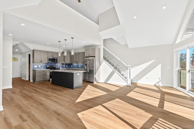 kitchen featuring backsplash, an island with sink, light hardwood / wood-style flooring, sink, and stainless steel appliances