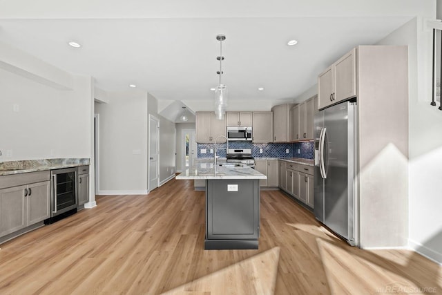 kitchen with stainless steel appliances, wine cooler, light wood-type flooring, gray cabinets, and light stone counters