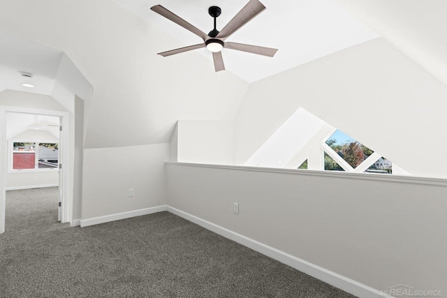 bonus room with lofted ceiling and dark colored carpet