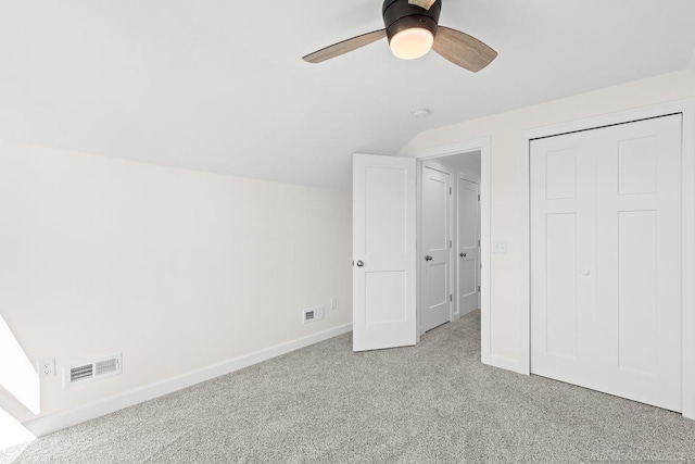 unfurnished bedroom with vaulted ceiling, light carpet, a closet, and ceiling fan