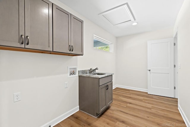 laundry room with sink, hookup for a washing machine, light hardwood / wood-style floors, and cabinets