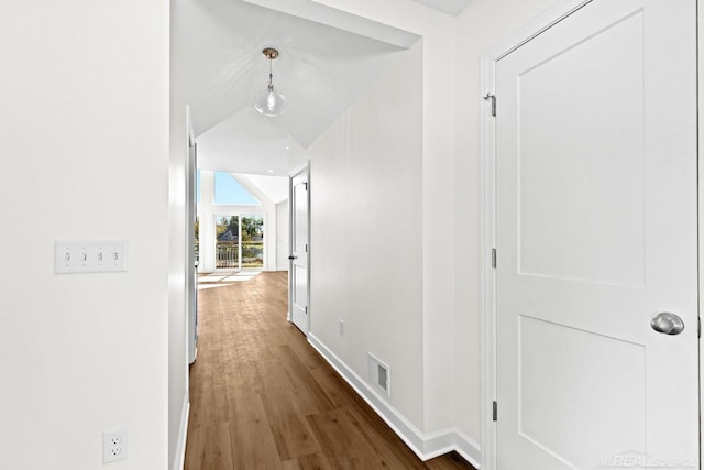 corridor with vaulted ceiling and dark hardwood / wood-style floors