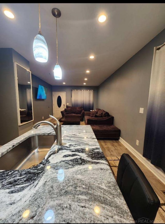 kitchen with sink, light stone countertops, and light hardwood / wood-style flooring