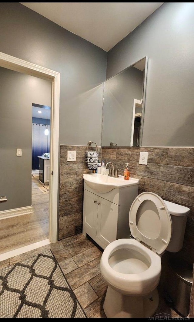 bathroom featuring vanity, toilet, wood-type flooring, and tile walls