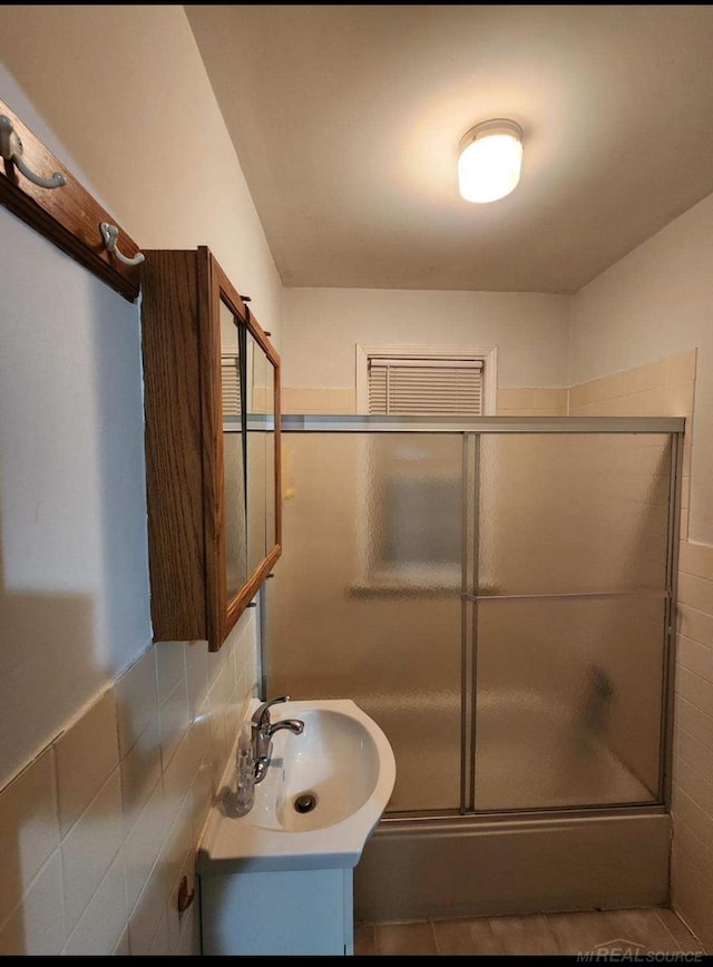 bathroom with a shower with door, vanity, tile walls, and tile patterned floors