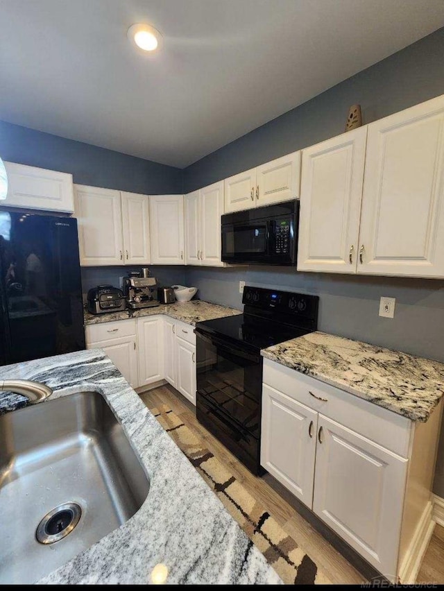 kitchen featuring black appliances, white cabinets, and light hardwood / wood-style floors