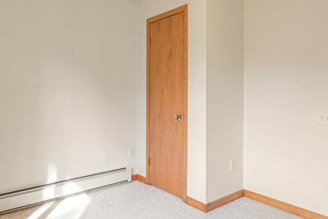 empty room with a baseboard radiator and light carpet