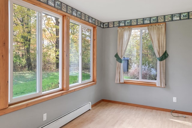 empty room with a healthy amount of sunlight, light hardwood / wood-style flooring, and baseboard heating