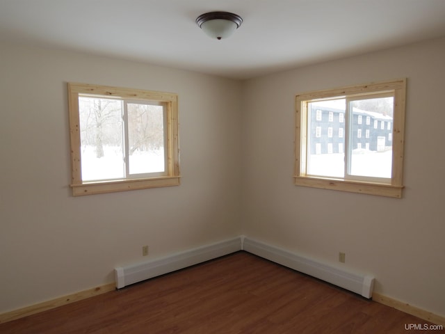 empty room with a baseboard radiator, wood-type flooring, and plenty of natural light