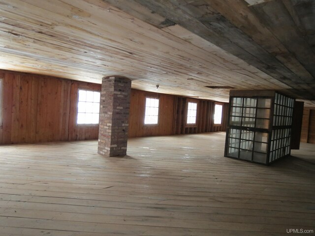 additional living space featuring light hardwood / wood-style floors, wood ceiling, wooden walls, and decorative columns