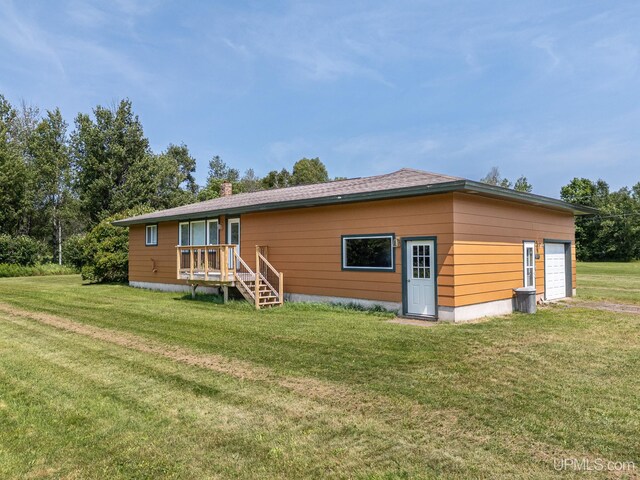 rear view of property featuring a garage and a lawn