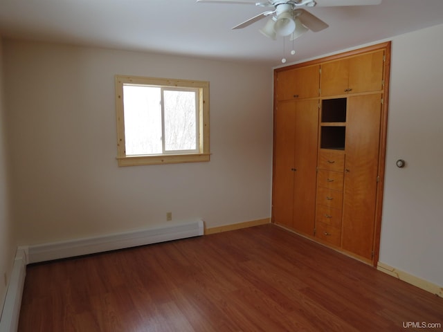 unfurnished bedroom featuring a closet, hardwood / wood-style flooring, baseboard heating, and ceiling fan