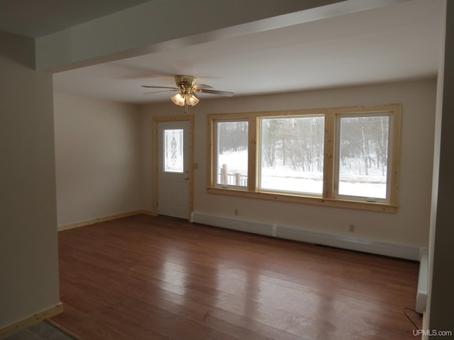 spare room featuring baseboard heating, hardwood / wood-style flooring, and ceiling fan