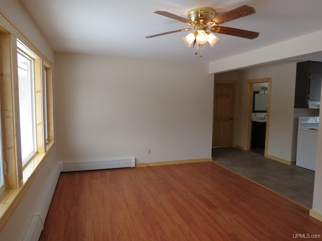 spare room featuring washer / clothes dryer, wood-type flooring, a baseboard heating unit, and ceiling fan