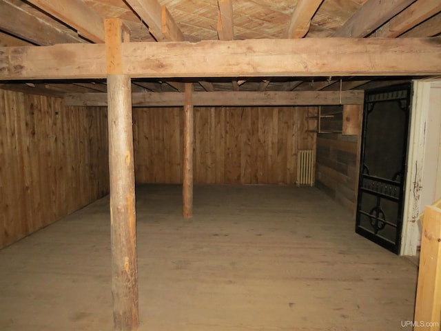 basement featuring wood walls and radiator heating unit