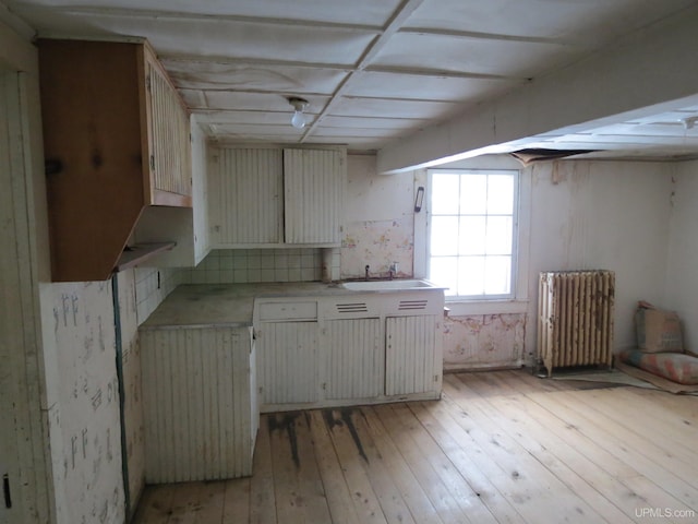 kitchen featuring sink, radiator heating unit, and light wood-type flooring