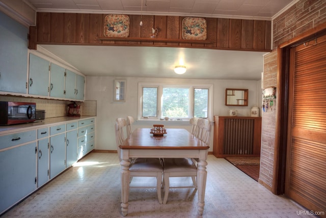 dining space featuring brick wall and crown molding