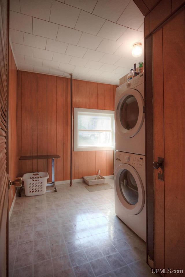 laundry area featuring stacked washer and dryer and wooden walls