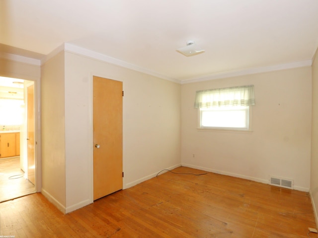 spare room featuring crown molding and light hardwood / wood-style floors