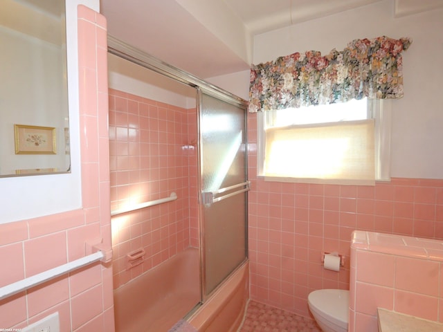 bathroom with tile walls, enclosed tub / shower combo, toilet, and tile patterned flooring