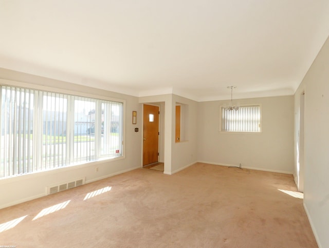 carpeted spare room featuring a notable chandelier