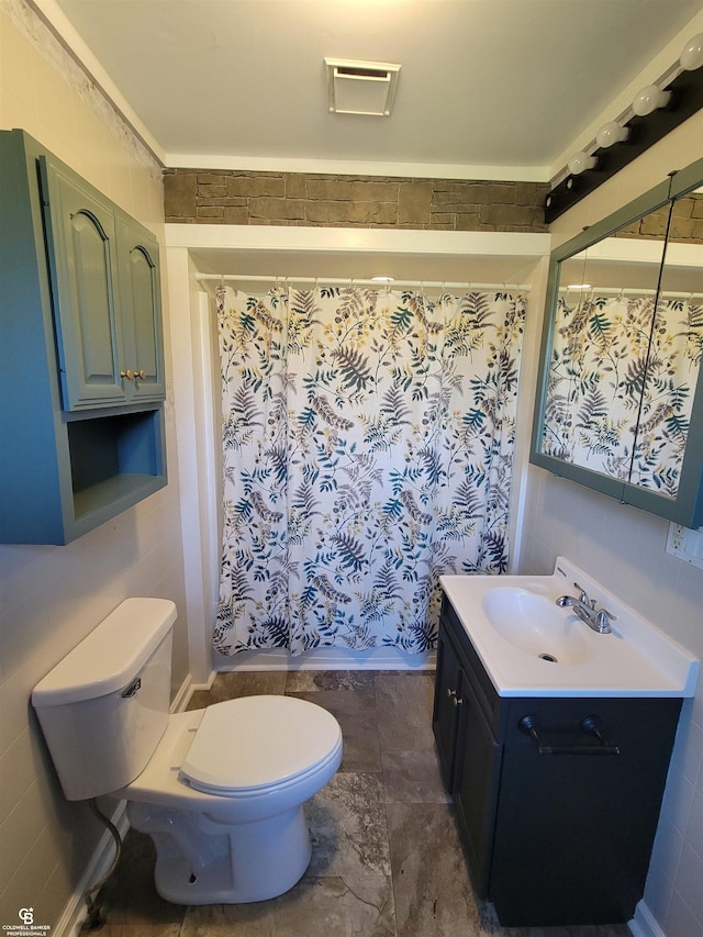 bathroom featuring toilet, curtained shower, vanity, and tile walls